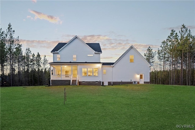 back house at dusk with a lawn and a porch