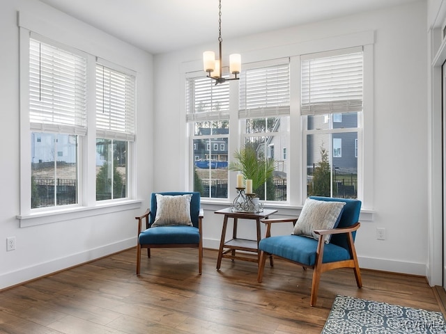 living area with a notable chandelier, baseboards, and wood finished floors