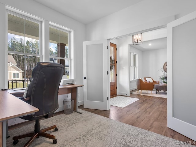 office area featuring a healthy amount of sunlight, a notable chandelier, baseboards, and wood finished floors