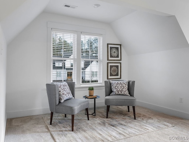 sitting room with carpet floors, lofted ceiling, visible vents, and baseboards