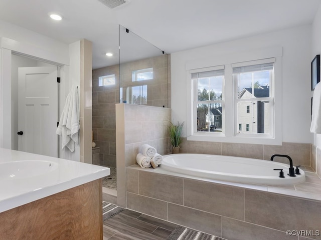 bathroom with visible vents, a garden tub, a walk in shower, a sink, and recessed lighting