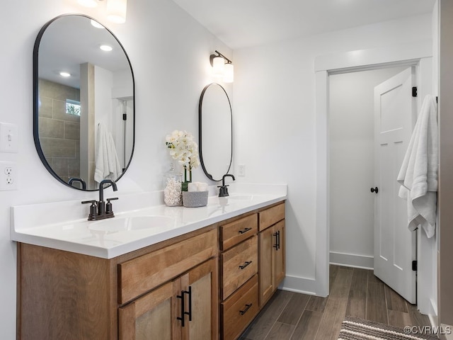 bathroom featuring double vanity, baseboards, a sink, and wood finished floors