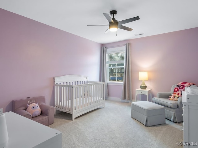 carpeted bedroom with a crib, ceiling fan, and visible vents