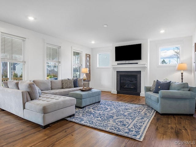 living area with recessed lighting, baseboards, wood finished floors, and a glass covered fireplace