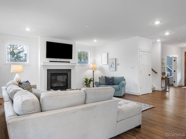 living room featuring recessed lighting, stairway, dark wood-type flooring, and a glass covered fireplace