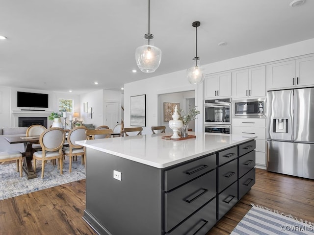 kitchen featuring dark wood-style floors, stainless steel appliances, a center island, and white cabinets