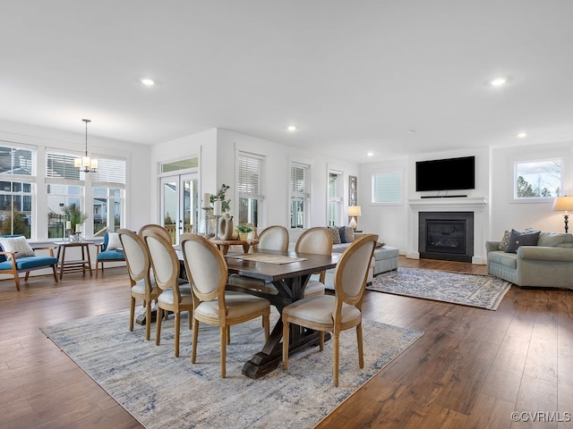 dining room featuring dark wood-style floors, a glass covered fireplace, french doors, and recessed lighting