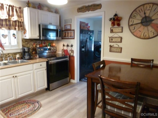 kitchen featuring washer / clothes dryer, white cabinetry, sink, and appliances with stainless steel finishes