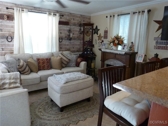 living room with wooden walls, ceiling fan, ornamental molding, and a wealth of natural light