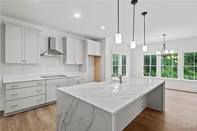 kitchen featuring a wealth of natural light, hanging light fixtures, wall chimney exhaust hood, and a spacious island