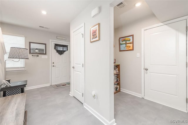 hall featuring baseboards, visible vents, and recessed lighting