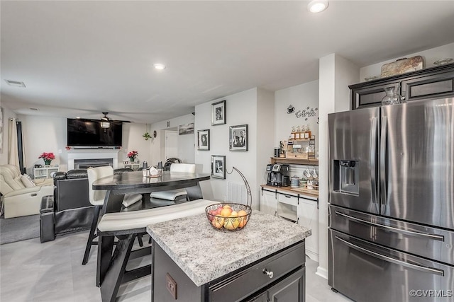 kitchen featuring visible vents, a kitchen island, open floor plan, light countertops, and stainless steel refrigerator with ice dispenser