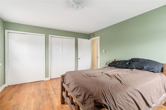 bedroom with multiple closets and light hardwood / wood-style flooring