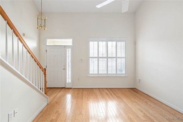 foyer entrance with ceiling fan with notable chandelier and light hardwood / wood-style flooring