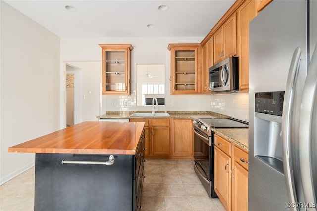 kitchen with stainless steel appliances, ceiling fan, sink, a kitchen island, and butcher block counters