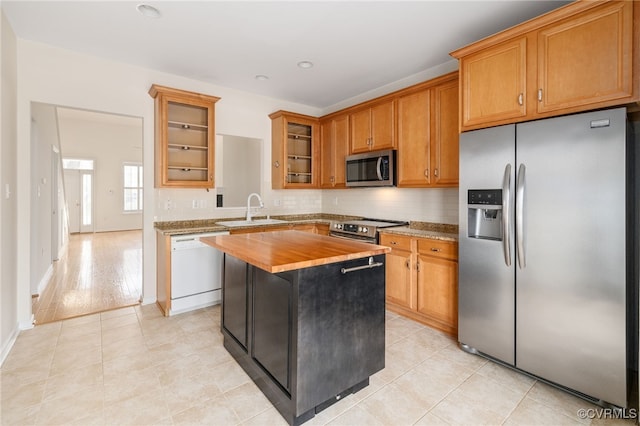 kitchen with sink, stainless steel appliances, a kitchen island, wooden counters, and light tile patterned flooring