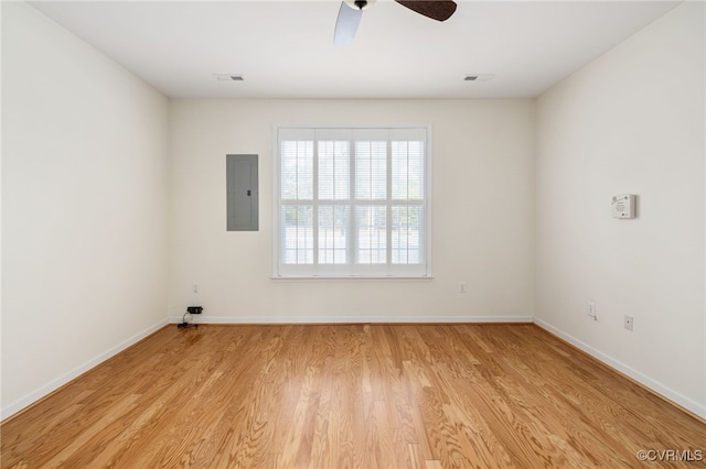 empty room with electric panel, light hardwood / wood-style flooring, and ceiling fan