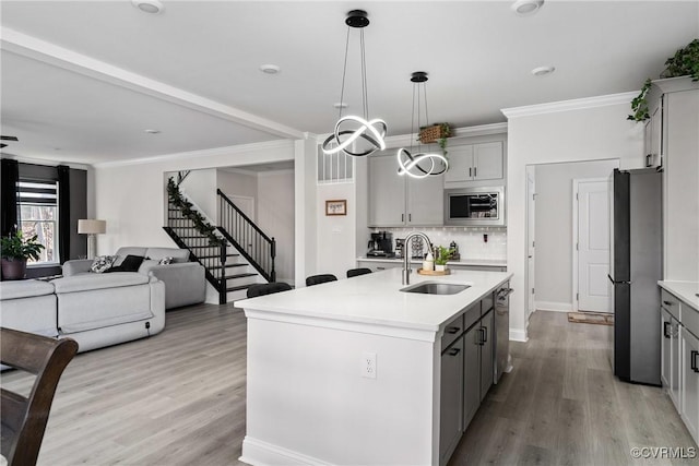 kitchen featuring gray cabinetry, a kitchen island with sink, sink, and stainless steel appliances