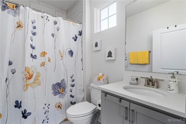 bathroom with walk in shower, vanity, and toilet