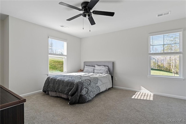 bedroom featuring ceiling fan, light colored carpet, and multiple windows