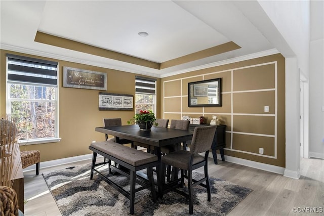 dining area with hardwood / wood-style floors, plenty of natural light, and a raised ceiling