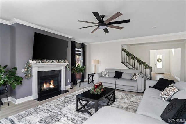 living room featuring light wood-type flooring, a wealth of natural light, ornamental molding, and ceiling fan