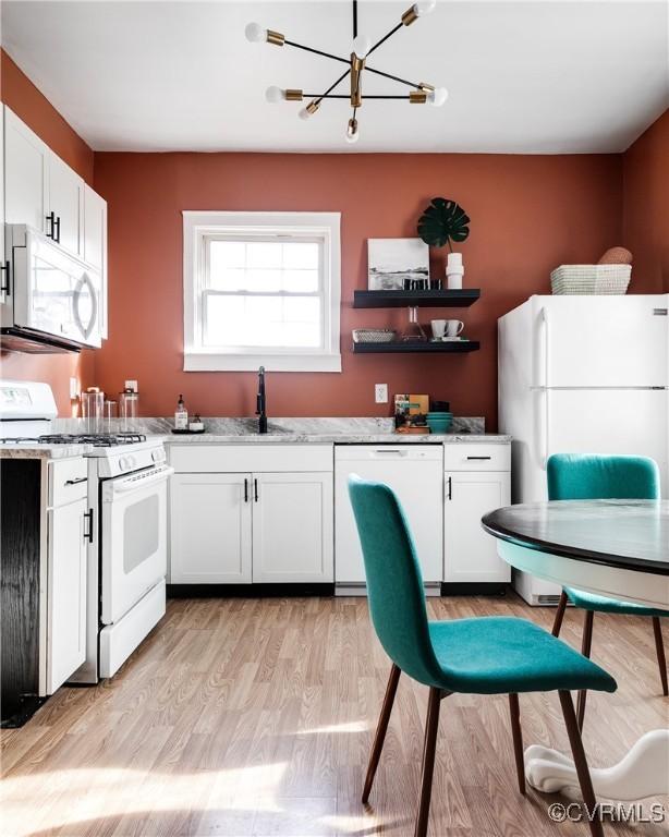 kitchen with white cabinetry, light stone countertops, white appliances, and light hardwood / wood-style flooring