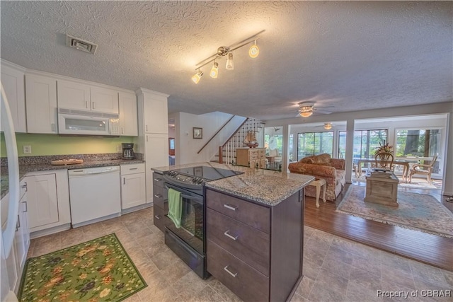 kitchen featuring white appliances, rail lighting, ceiling fan, a kitchen island, and white cabinetry