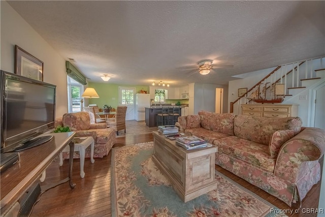 living room with hardwood / wood-style floors, a textured ceiling, and ceiling fan