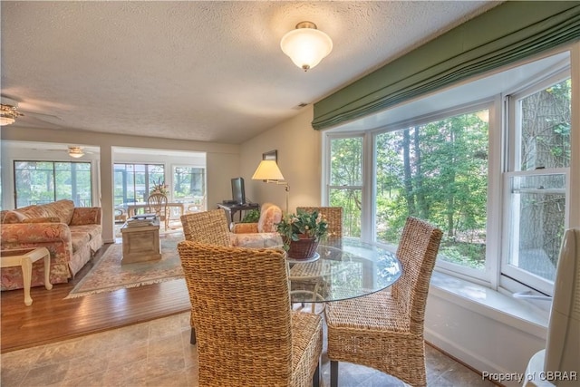 dining space featuring ceiling fan, light wood-type flooring, and a textured ceiling