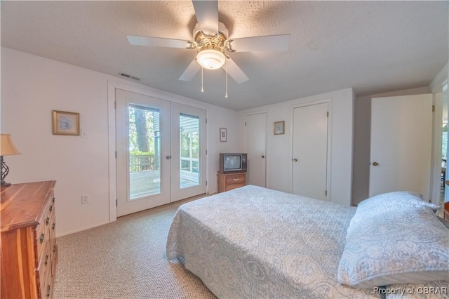 carpeted bedroom with ceiling fan, access to exterior, a textured ceiling, and french doors