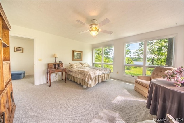 bedroom with multiple windows, ceiling fan, and light carpet