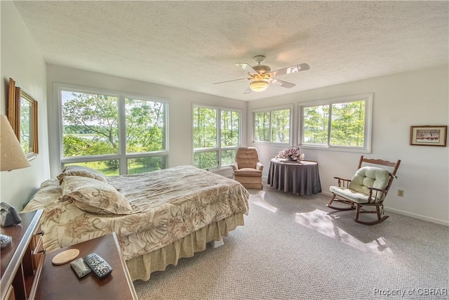 carpeted bedroom featuring ceiling fan and a textured ceiling