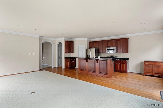 kitchen with arched walkways, light wood-style flooring, a breakfast bar, open floor plan, and stainless steel appliances