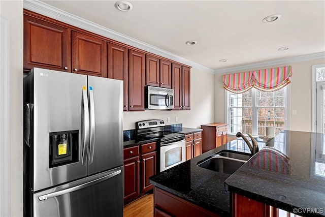 kitchen featuring stainless steel appliances, crown molding, a sink, and an island with sink