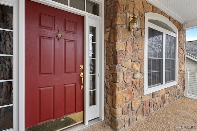 property entrance featuring stone siding and covered porch