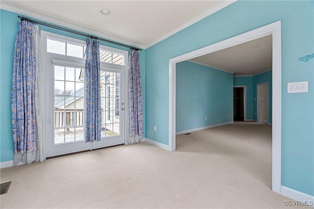 carpeted empty room featuring baseboards and crown molding