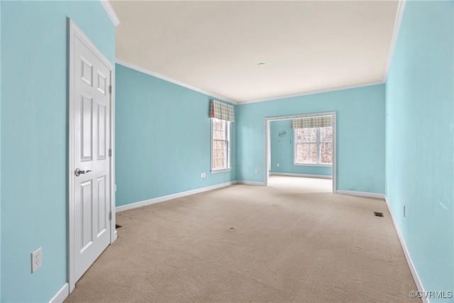 carpeted empty room featuring crown molding and baseboards