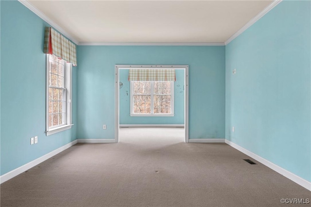 carpeted empty room featuring ornamental molding, visible vents, and baseboards