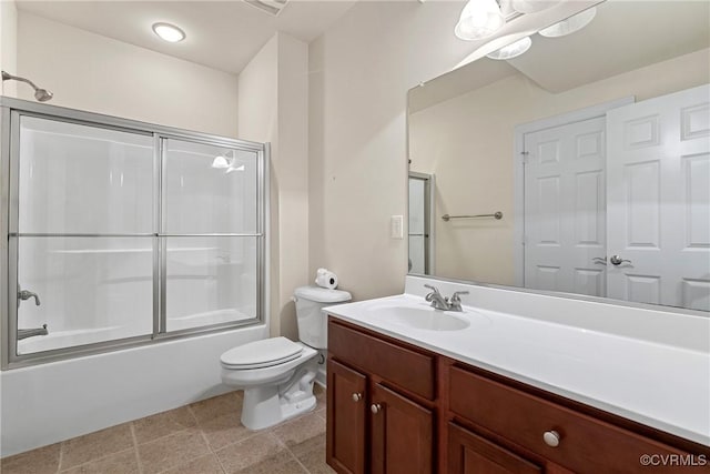 bathroom featuring tile patterned floors, vanity, toilet, and bath / shower combo with glass door