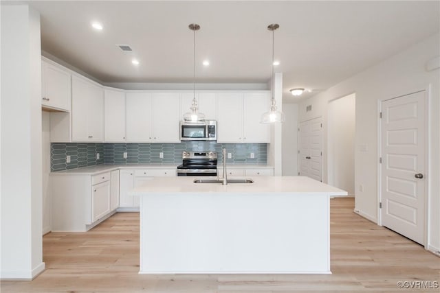 kitchen featuring white cabinets, sink, light hardwood / wood-style flooring, decorative light fixtures, and stainless steel appliances