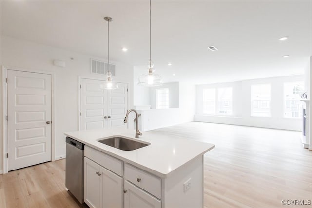 kitchen with sink, pendant lighting, light hardwood / wood-style flooring, dishwasher, and an island with sink