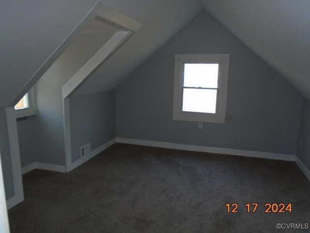 additional living space with dark carpet and vaulted ceiling