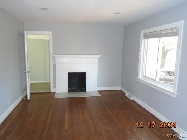 unfurnished living room featuring dark hardwood / wood-style floors and a brick fireplace