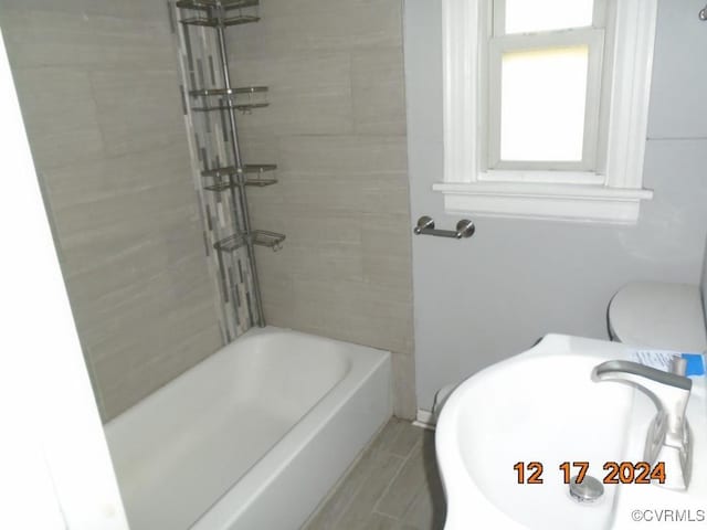 full bathroom featuring toilet, tiled shower / bath, and sink