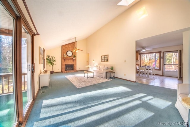 unfurnished living room with carpet flooring, a skylight, high vaulted ceiling, and ceiling fan