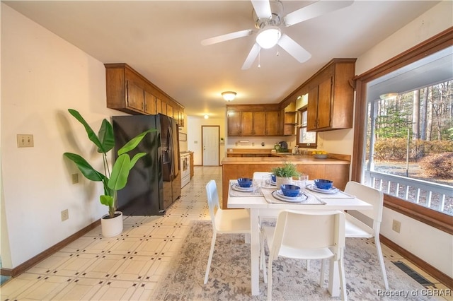 kitchen featuring a breakfast bar, white range with electric cooktop, black fridge, sink, and ceiling fan