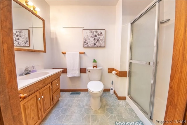 bathroom featuring tile patterned flooring, vanity, toilet, and an enclosed shower