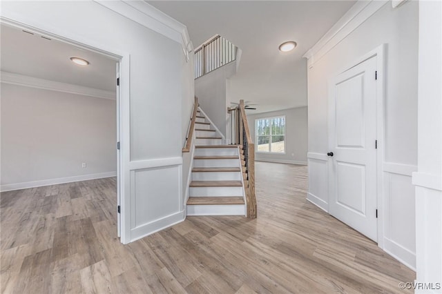 stairs with wood finished floors, baseboards, and ornamental molding