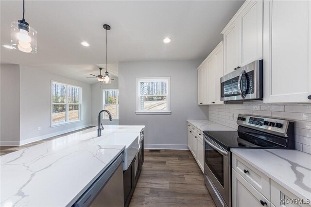 kitchen featuring appliances with stainless steel finishes, dark hardwood / wood-style flooring, white cabinetry, and pendant lighting